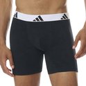 Model draagt zwarte boxershort met witte adidas tailleband.