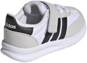 Witte kindersneaker met zwarte strepen, klittenbandsluiting en een zwarte hiel met logo, van achteren gezien.