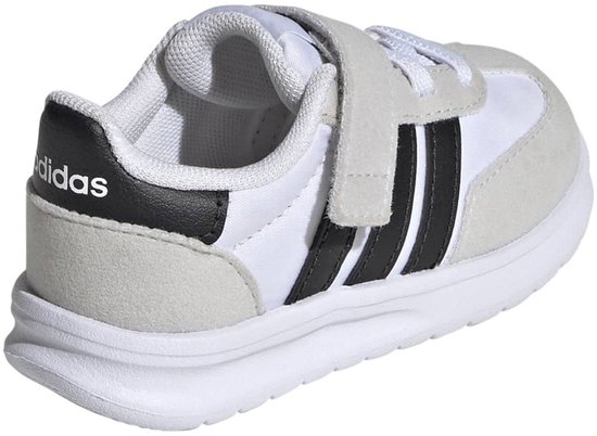 Witte kindersneaker met zwarte strepen, klittenbandsluiting en een zwarte hiel met logo, van achteren gezien.