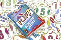Doosspel FLIP 7: turquoise met gele letters en kaarten, omringd door speelkaarten met cijfers