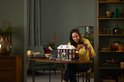 Vrouw bouwt een LEGO huis. Op de achtergrond een kerstboom en LEGO huismodel.