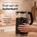 Hand raakt de dubbelwandige, koele buitenkant van de zwarte waterkoker aan.