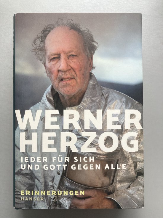 Boek kaft met Werner Herzog in zilveren jas. Titel: "Jeder für sich und Gott gegen alle".