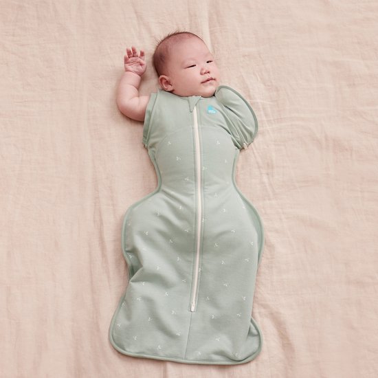 Baby in lichtgroene omslagdoek met twijgjespatroon, zijkant met een geopende mouw.