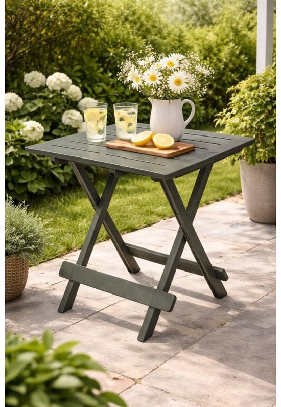 Groene, opklapbare campingtafel met geprononceerde houten structuur, met een kan bloemen en citroenen erop.
