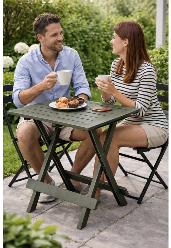 Groene, opklapbare campingtafel met geprononceerde houten structuur, gefotografeerd met twee personen buiten.