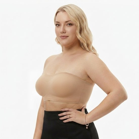 Volslanke vrouw met blonde krullen draagt een nude strapless BH met voorgevormde cups. Ze draagt een zwarte rok.