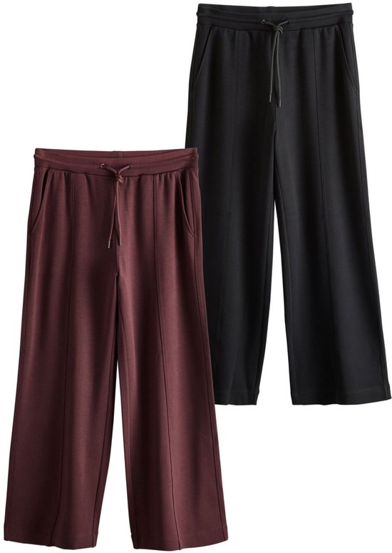 Een bordeauxrode en een zwarte joggingbroek met wijde pijpen.