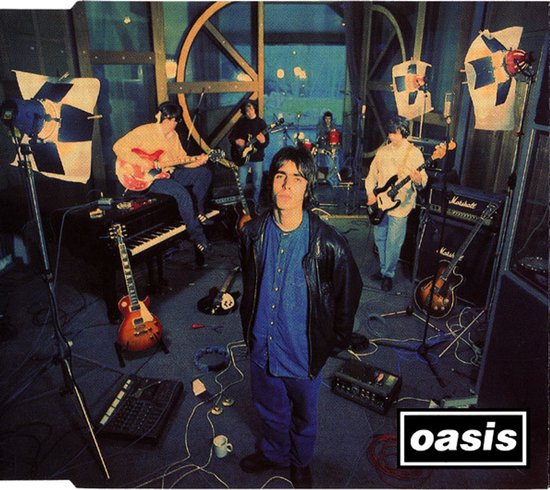 Oasis band in studio met piano, gitaren en versterkers. Liam Gallagher staat vooraan.