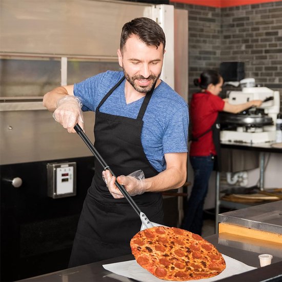 Een man met een schort gebruikt een pizzaschep om een pepperoni pizza uit een oven te halen.