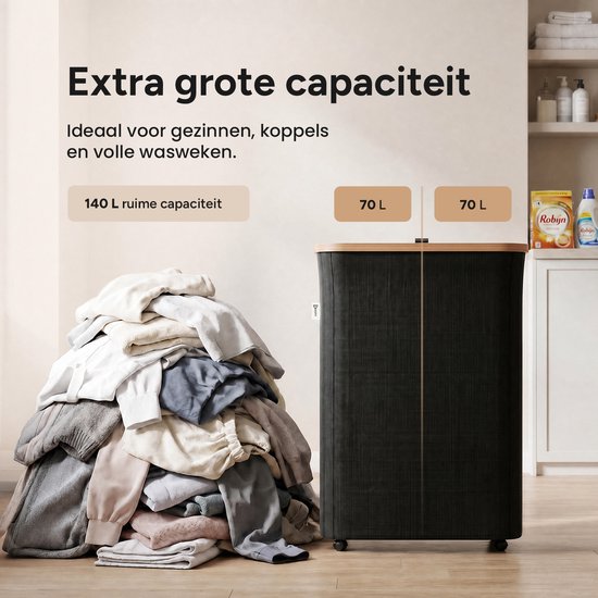 Een berg wasgoed van 140 liter naast een zwarte wasmand met bamboehouten deksel op wieltjes in een badkamer. De wasmand heeft 2 vakken van 70L.