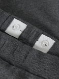 Sluiting van verstelbare tailleband met knopen aan de binnenkant van een donkergrijze joggingbroek.