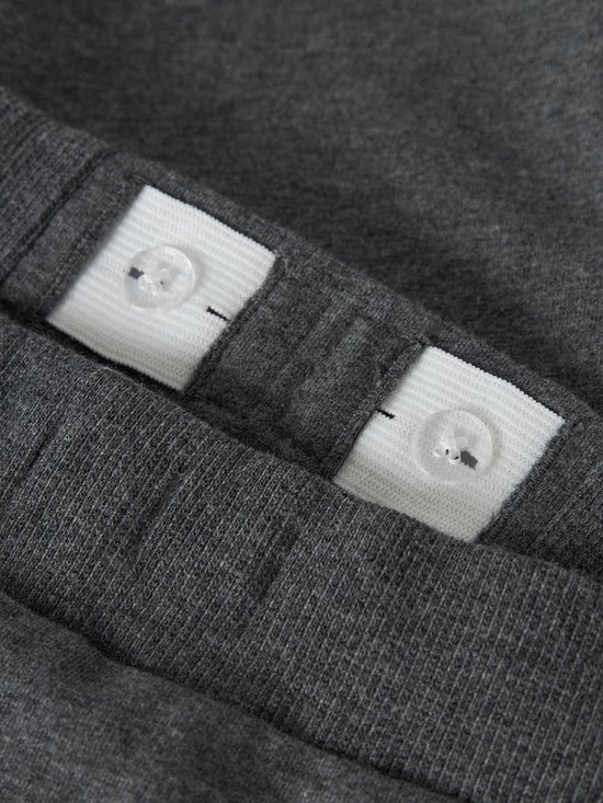 Sluiting van verstelbare tailleband met knopen aan de binnenkant van een donkergrijze joggingbroek.