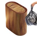 Ovale prullenbak met houtlook en klapdeksel, naast een hand die een zwarte vuilniszak vasthoudt.