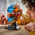 Man kijkt naar een LEGO McLaren F1 helm, blauw en oranje, met Lego-figuurtje.