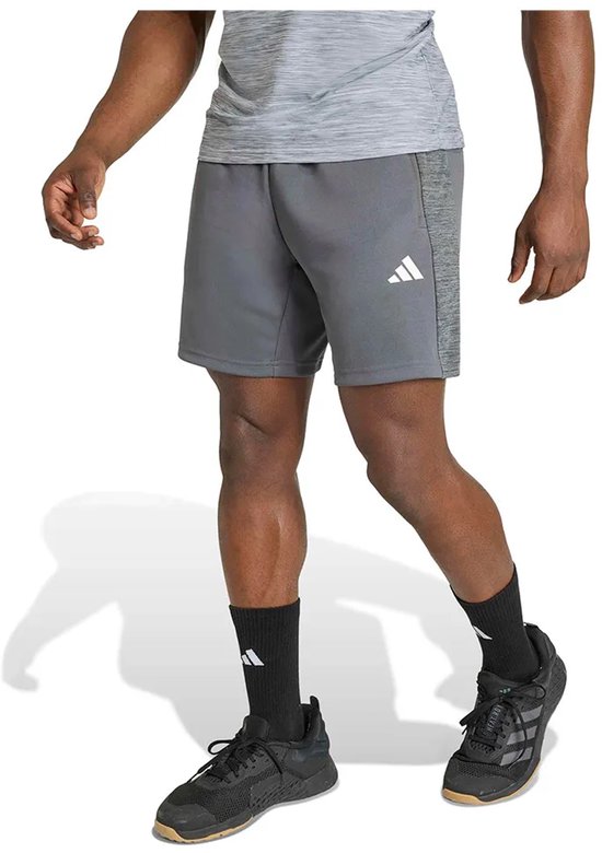 Model draagt grijze sportbroek met wit Adidas-logo op de dij en donkergrijze zijpanelen.