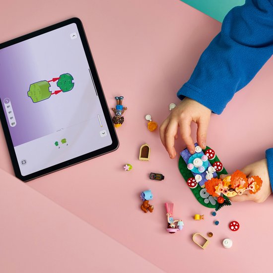 Kind speelt met LEGO Friends bosfeest onderdelen en tablet met bouwinstructies.