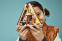 Kind houdt een Lego Friends speelgoedhuisje met roze accenten vast.