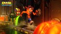 Crash Bandicoot staat voor een bedieningspaneel in een fabriek, met groene vloeistof.