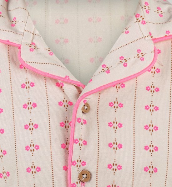 Naden van een gebroken witte pyjamatop met verticale roze-bruine bloemetjes, roze biezen en houten knopen.