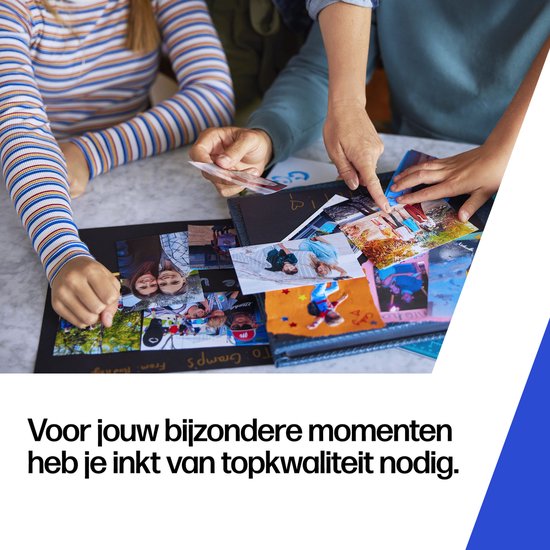 Twee personen bekijken foto's en een fotoalbum op een tafel. Ze kiezen foto's uit.