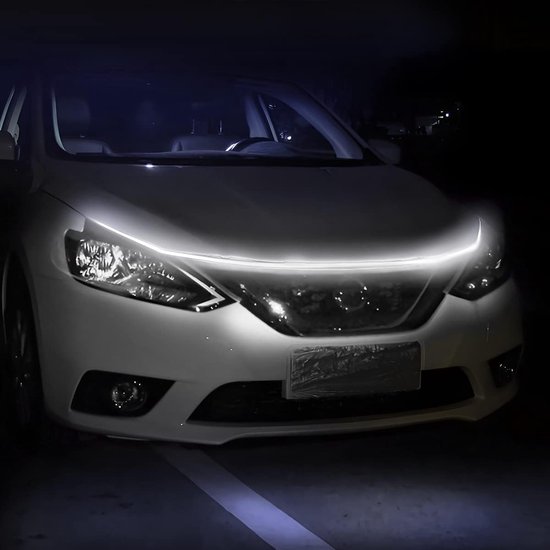 Een witte auto met een helder witte LED strip op de motorkap, 's nachts.