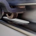 Een wit, ovaal deurslot dat tussen de rails van een camper schuifdeur is geplaatst.