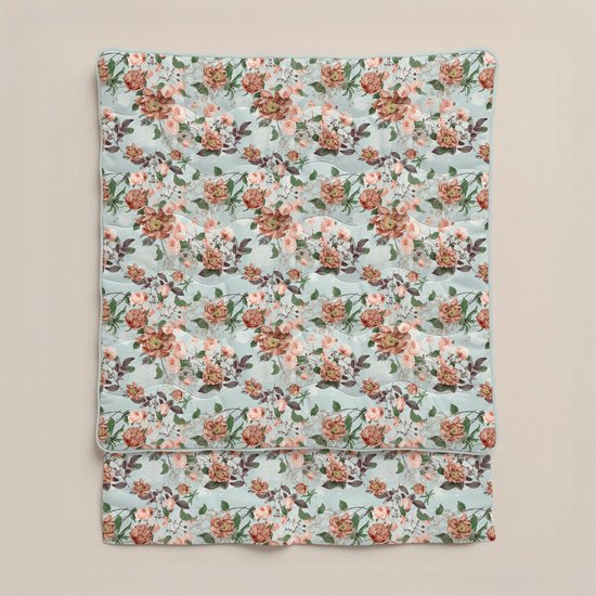 Een gevouwen lichtgroen dekbed met een print van roze en oranje bloemen en groene bladeren.