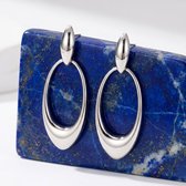 Zilverkleurige, ovale oorhangers met een gepolijste afwerking, hangend aan een zilverkleurige staaf, op een lapis lazuli steen.