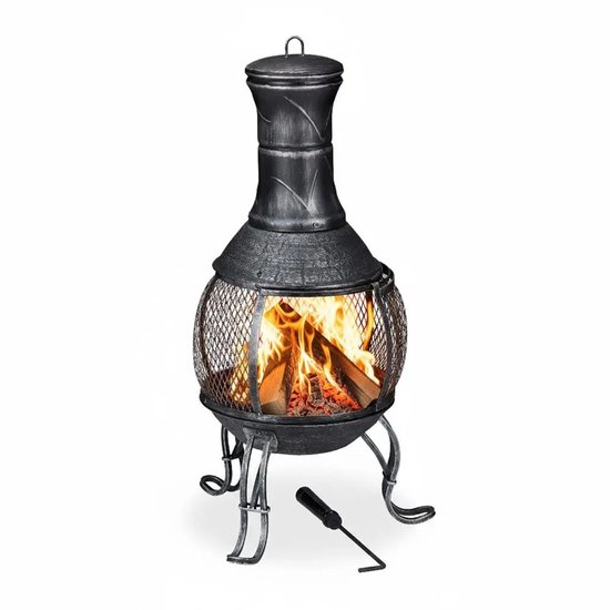 Zwarte metalen terrashaard met verhoogd rooster en brandend hout. Pook ligt ernaast.