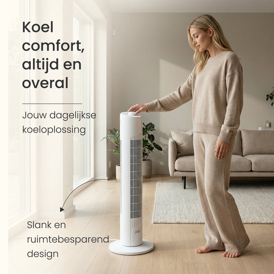 Een vrouw in een beige outfit raakt de witte JAP torenventilator aan in een woonkamer.