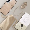Beige telefoonhoesje met croco-textuur, pasvakje, draagkoord, stofzak en verpakking.