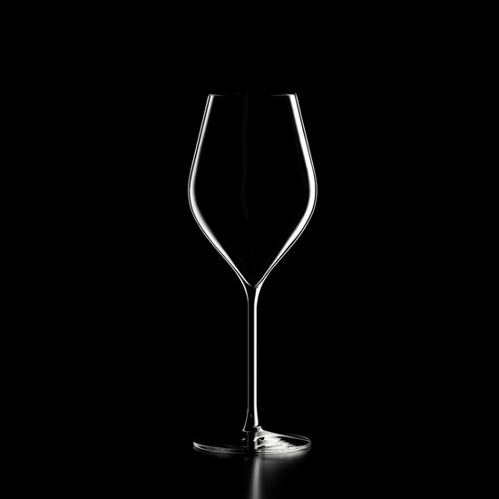 Een leeg, helder wijnglas met slanke steel en brede kelk, met een lichte reflectie op de ronde voet. Geïsoleerd op een zwarte achtergrond.