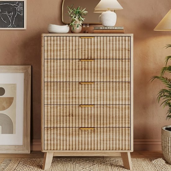 Houten ladekast met 5 golvende fronten en gouden handgrepen, in een gestylede slaapkamer.