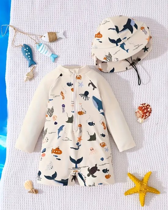 Een crème zwempak met lange mouwen en bijpassend zonnehoedje, beide met een print van zeedieren zoals walvissen, schildpadden en kwallen.