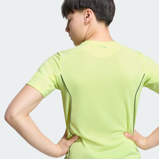 Jongen in geel T-shirt met korte mouwen, rug zichtbaar met donkere biezen en Adidas Climacool logo.