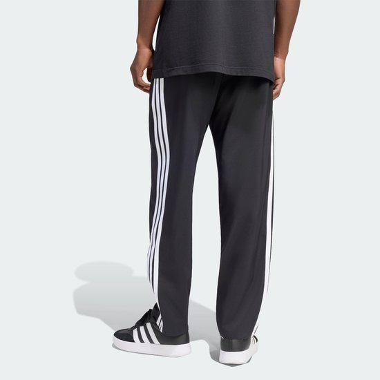 Zicht op de achterkant van een zwarte sportbroek met witte Adidas strepen op de zijkant.