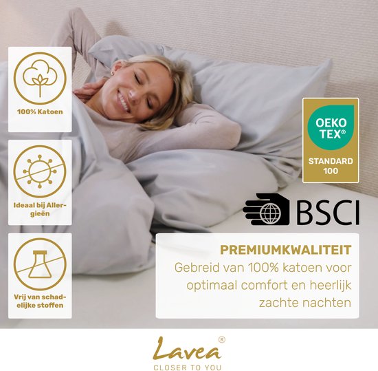 Vrouw lacht onder grijs beddengoed. Logo's tonen '100% Katoen', 'Ideaal bij Allergieën', 'Vrij van schadelijke stoffen', OEKO-TEX®, BSCI.