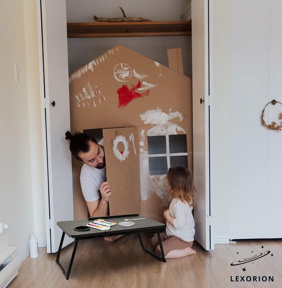 Man en kind spelen met knutselhuisje in een kast. Bedtafel met verf, telefoon en smartphone ernaast.