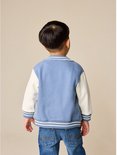 Achterkant van een blauw-wit bomberjack op een kind met jeans.