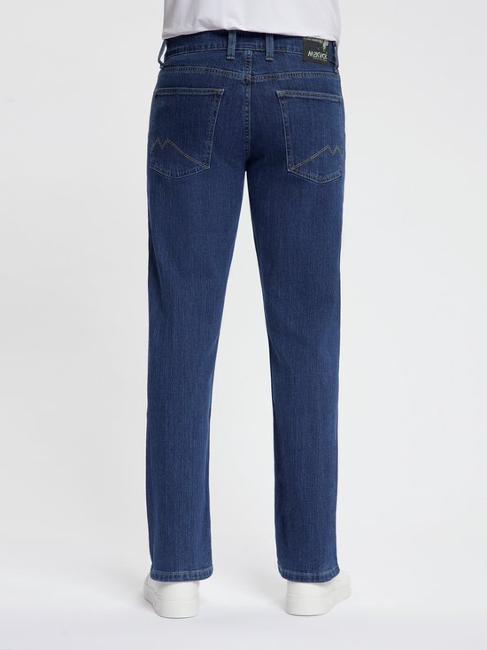 Achterkant van een man in donkerblauwe jeans met gele stiksels en wit T-shirt.