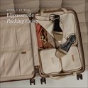 Crème packing cubes verpakt in een open koffer met kleding en schoenen.
