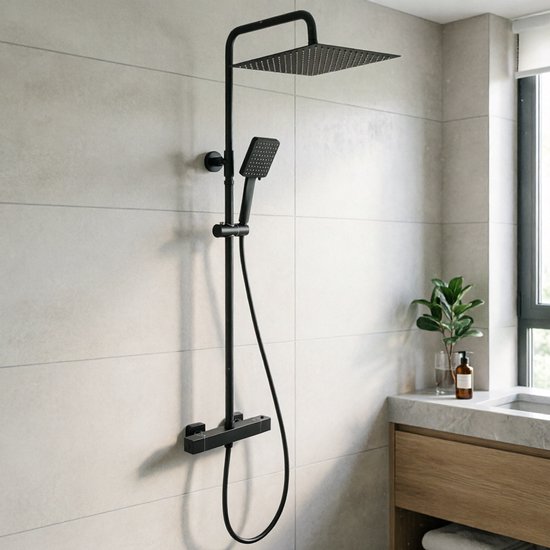 Zwarte doucheset met vierkante douchekop en handdouche, gemonteerd op een grijze betegelde muur naast een wastafel.