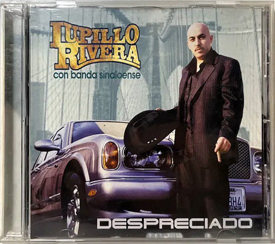 Lupillo Rivera in een donker gestreept pak met hoed voor een luxe auto. Albumtitel: Despreciado met banda sinaloense.