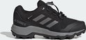 Zwarte kinderschoen met grijze Adidas-strepen en grijze zool.