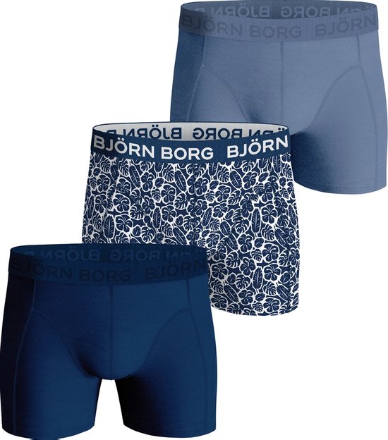 Drie boxershorts van Björn Borg: twee effen donkerblauw en lichtblauw, één met bladerprint.