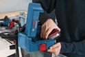 Persoon plaatst een 18V Bosch Professional-accu in de blauwe GAS 18V-10 L bouwstofzuiger.