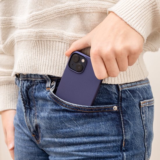 Donkerblauwe telefoonhoes die in een spijkerbroekzak wordt gestopt.