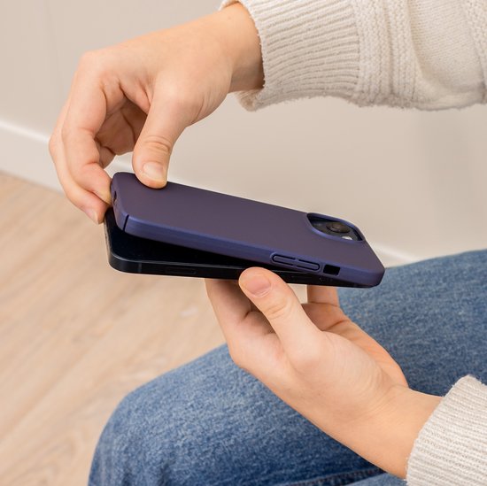 Handen plaatsen een donkerblauw hoesje op een iPhone.