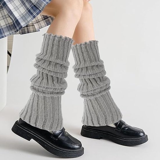 Grijze, grof gebreide beenwarmers van acryl met ruches aan de bovenkant, gedragen met zwarte schoenen.